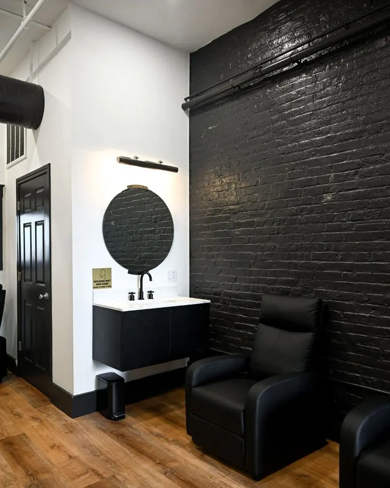 Lobby/waiting nook at Boston Beautox with black leather chairs and exposed black brick wall