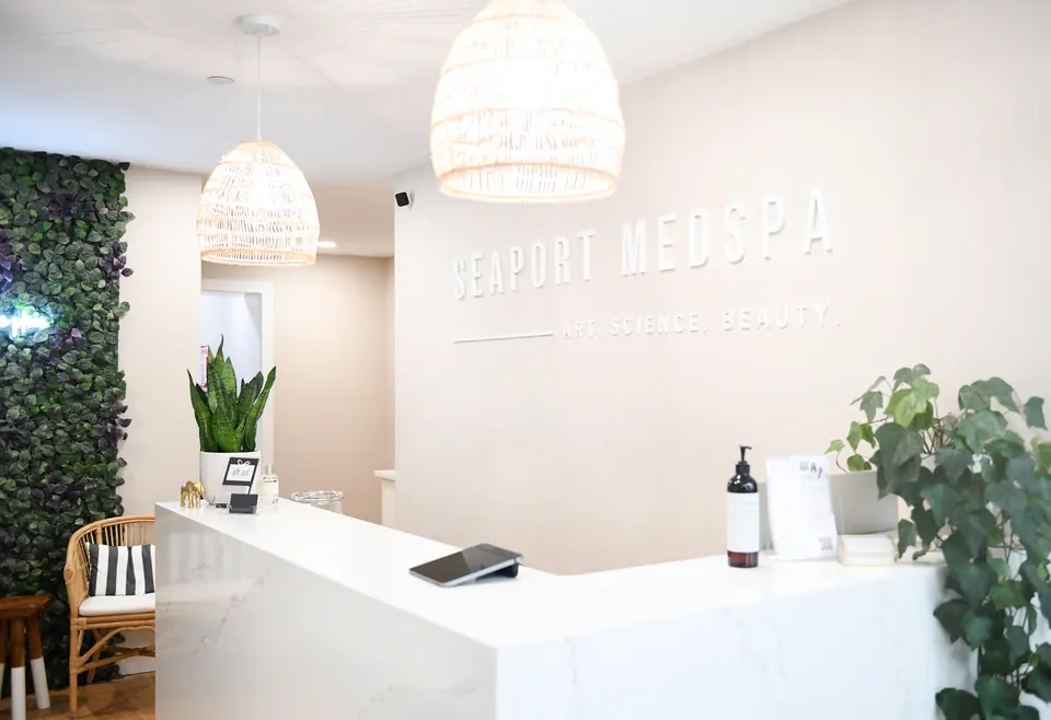 Reception desk at Seaport Medspa South Boston with illuminated 'Seaport Medspa, Art. Science. Beauty.' wall sign