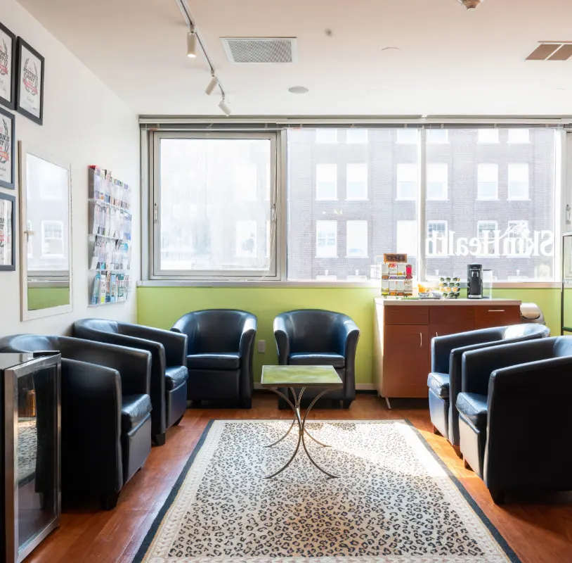 Waiting area at SkinHealth Centers Boston with leather armchairs and city-view windows